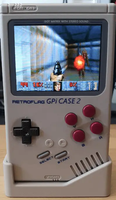 The GPi Case 2, stood upright in a dock. Showing a screenshot of Doom being played.