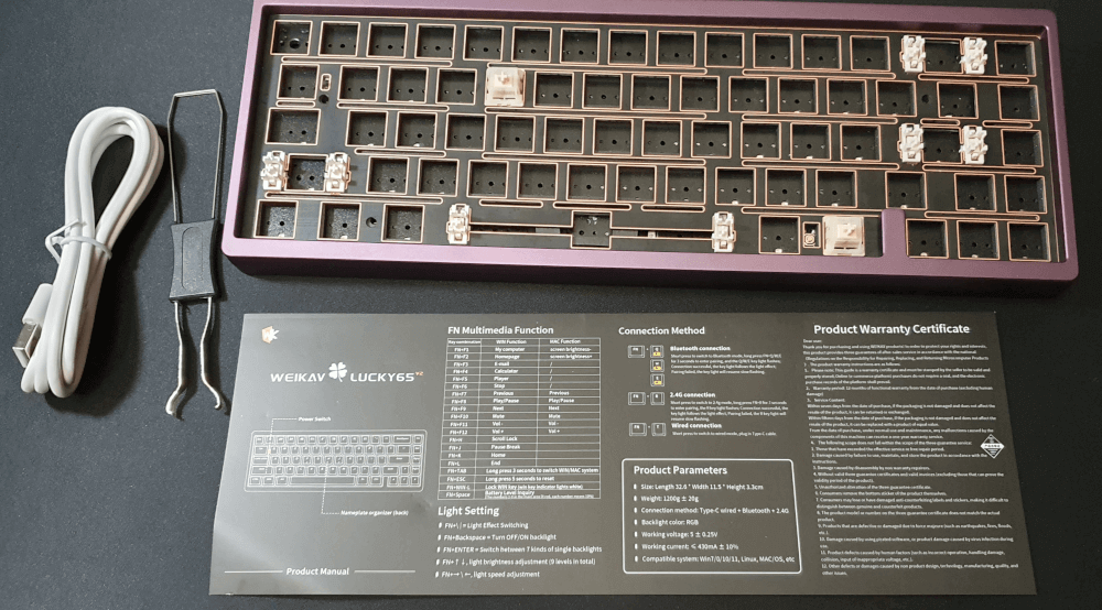 A freshly unblocked Weikav Lucky65 V2 keyboard. Showing a blank keyboard with two holder switches, a usb cable, a switch puller and an instruction card.